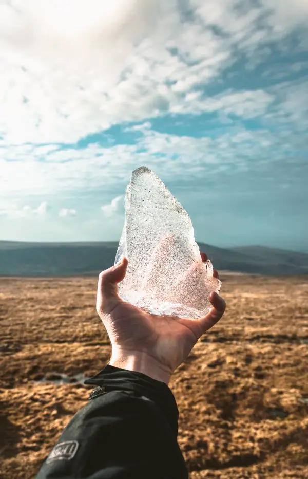 A person holding ice outdoors during the day.